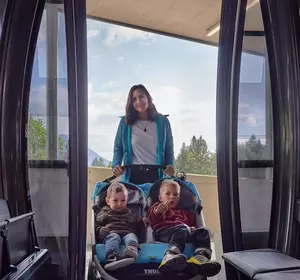 Mutter mit Kindern im Kinderwagen steigt in die Gondel ein