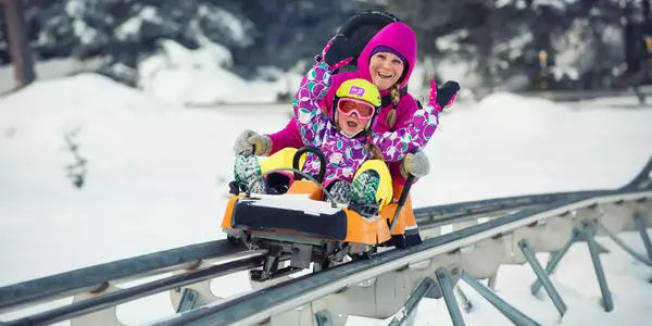 Mutter und Kind beim Alpine Coaster fahren im Winter in Hoch-Imst