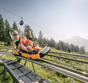 Frau mit Kind fahren mit der Sommerrodelbahn Alpine Coaster Imst im Sommer