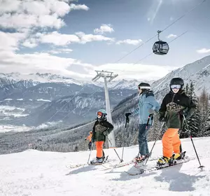 Familie beim Skifahren auf der Alpjoch-Abfahrt in Imst mit Gondel im Hintergrund