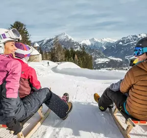 Familie beim Rodeln im Winter in Imst im Tirol